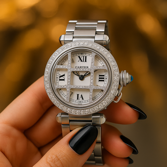 A Cartier diamond-encrusted luxury watch held by a hand with black polished nails, set against a blurred golden background, showcasing elegance and fine craftsmanship.