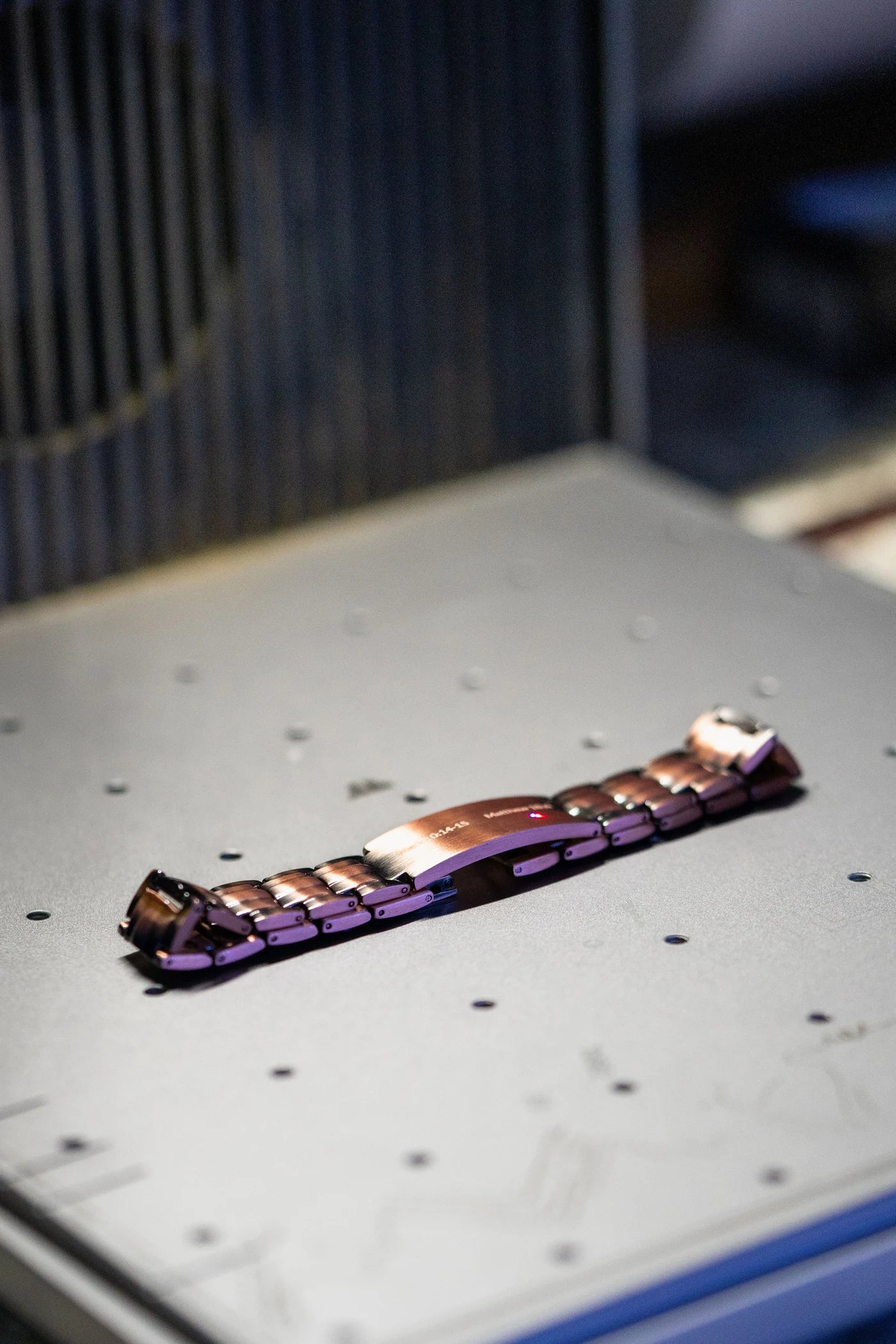 Metal watch bracelet clasp positioned inside an engraving machine