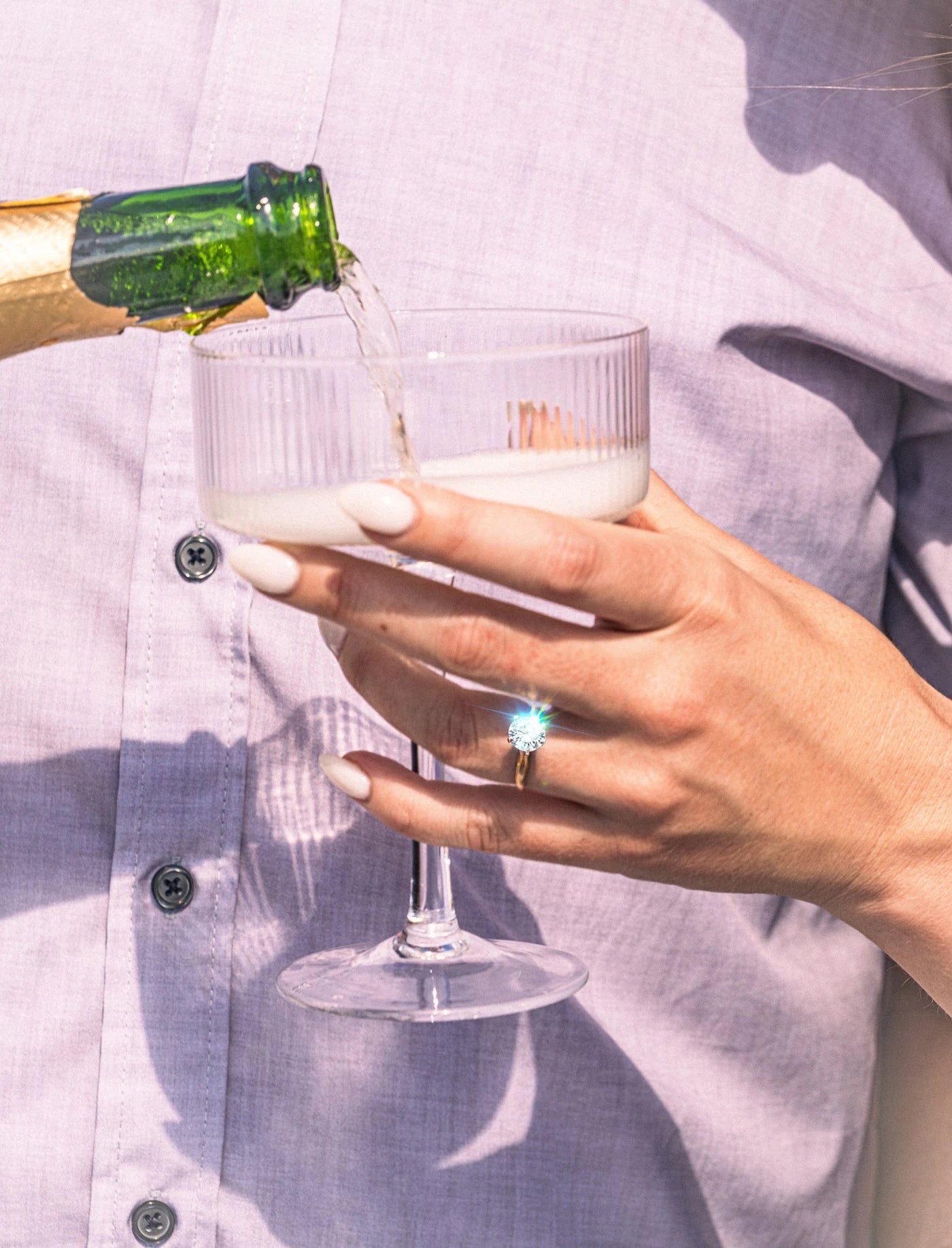 Hands holding glasses during a celebration, with a ring visible
