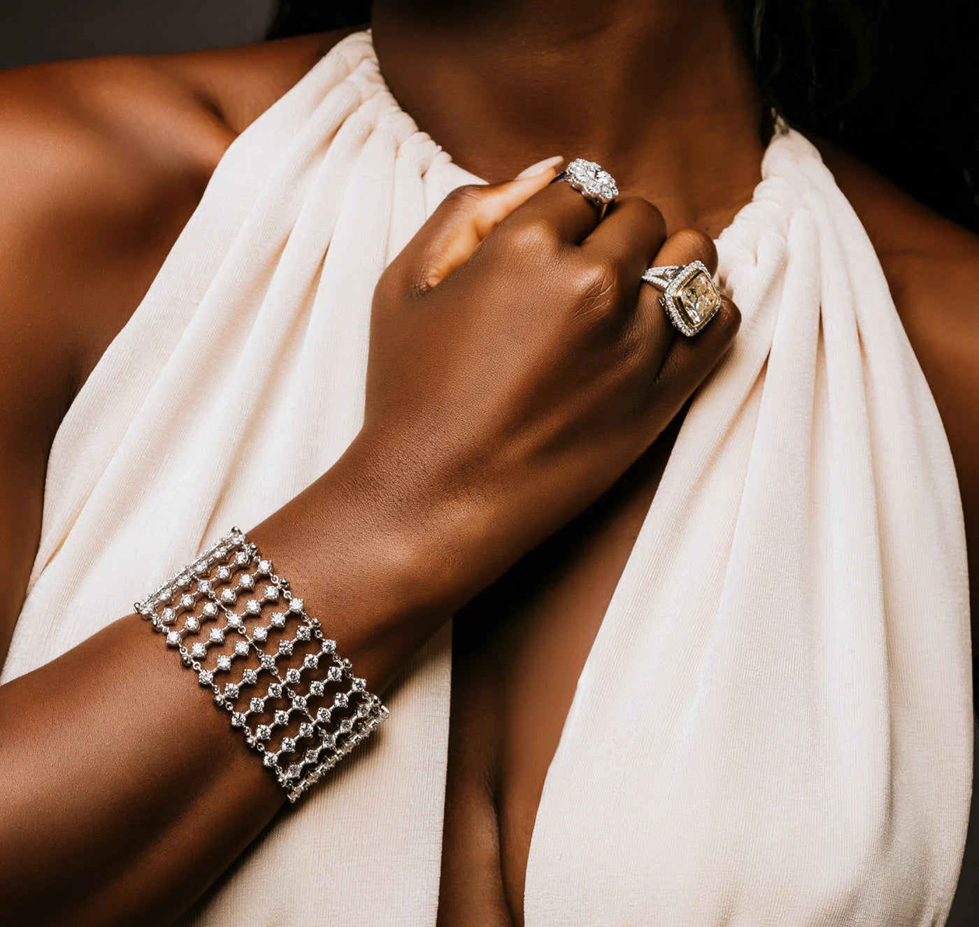 Wide stone set bracelet and statement rings worn with a white dress