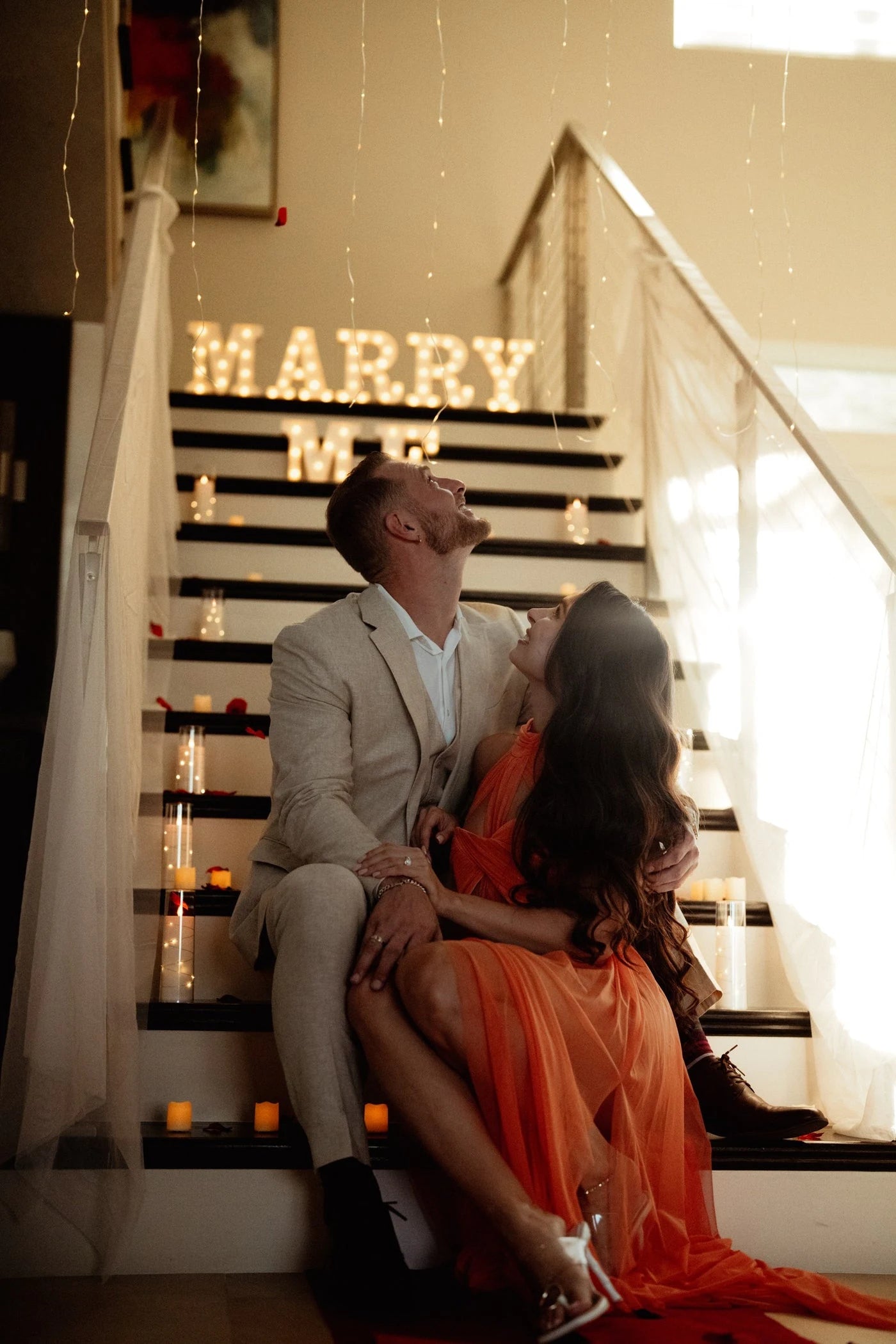 Couple seated beside a proposal display with Marry Me lettering