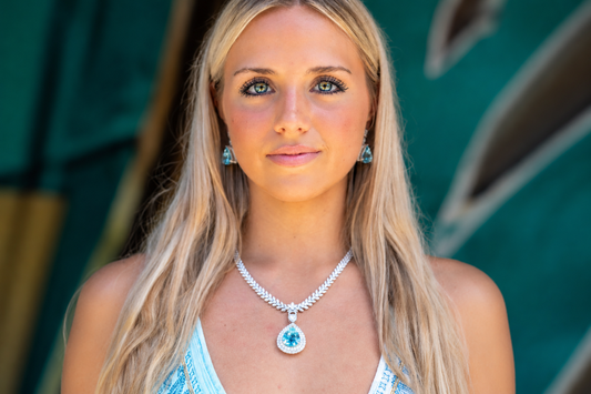Model wearing a pale blue pendant necklace with matching earrings.