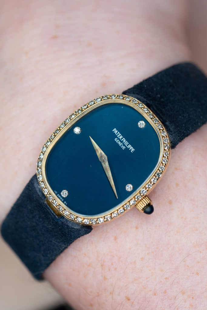 Patek Philippe watch with blue dial, gemstone set bezel and dark strap