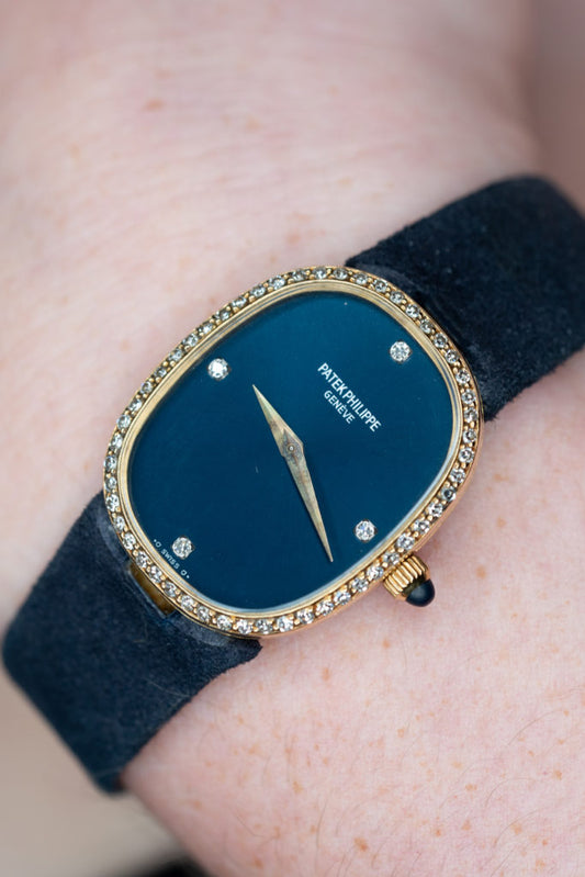 Patek Philippe watch with blue dial, gemstone set bezel and dark strap