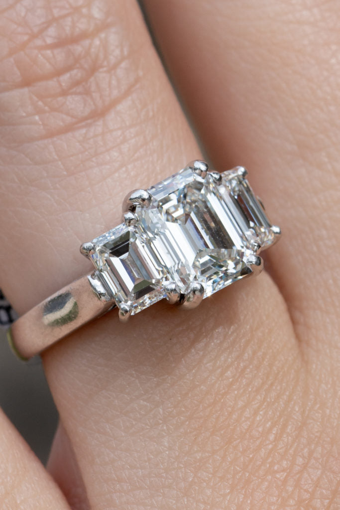 Rectangular step cut center stone with two rectangular side stones.