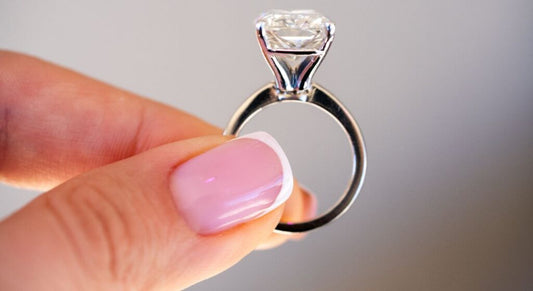 A side view of a solitaire ring held between fingers.