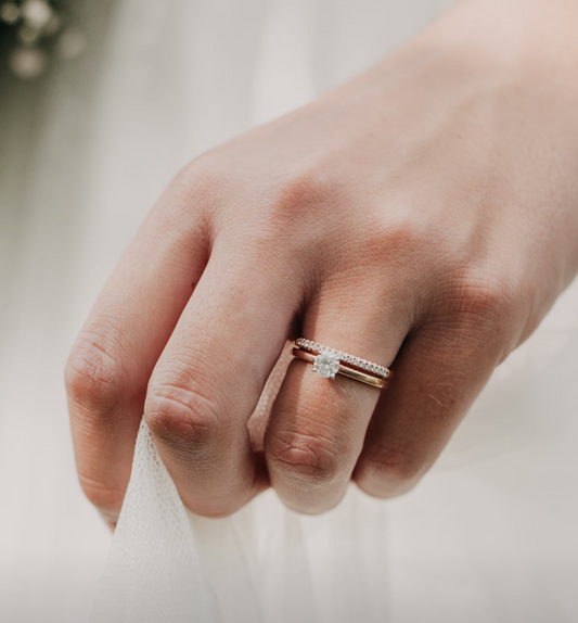 A small center stone ring worn beside a narrow stone set band.