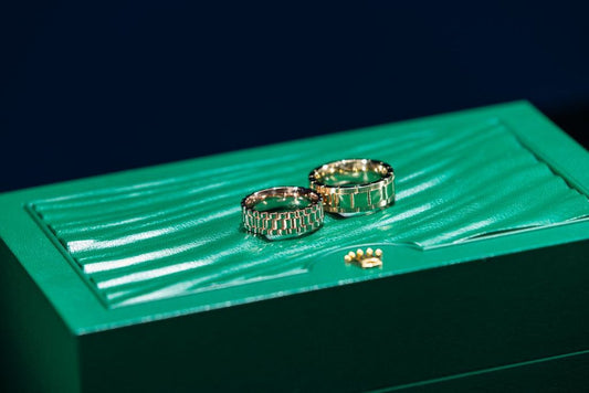 Two rings with bracelet link patterns on a green display box.