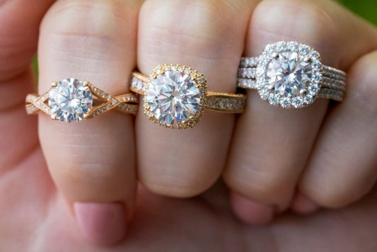 Three engagement rings with round center stones in different settings.