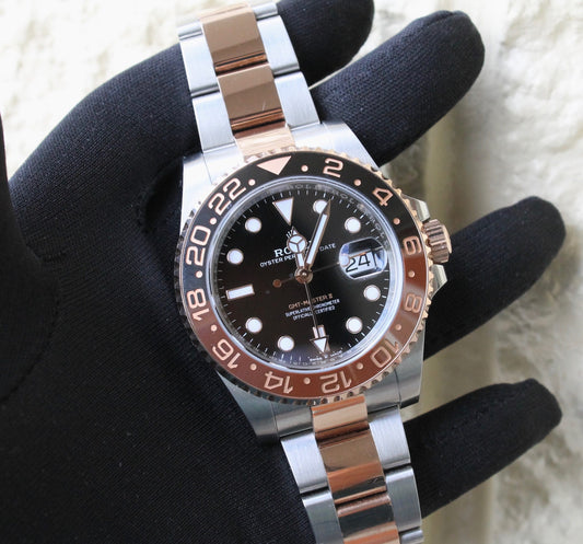 Two tone GMT Master II with a brown and black bezel held in a gloved hand.