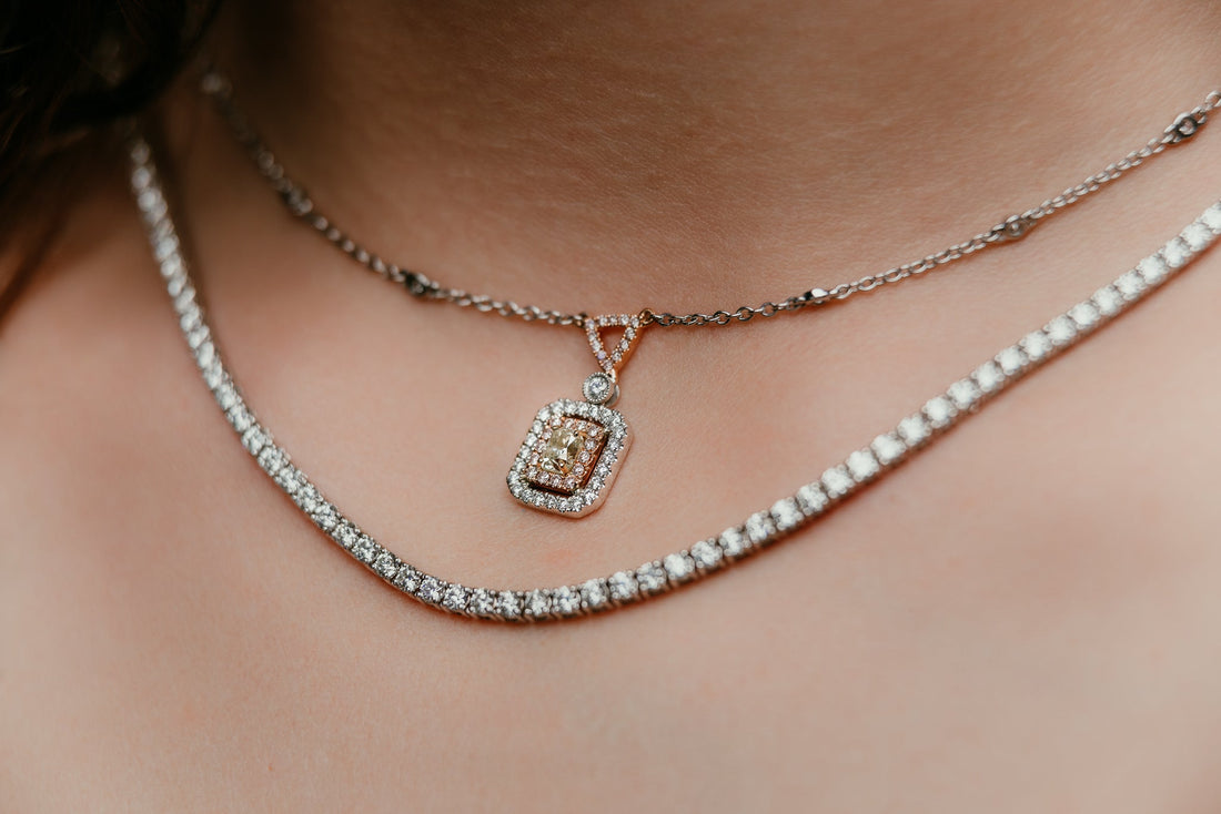 Close-up of a person's neck wearing two layered diamond necklaces.