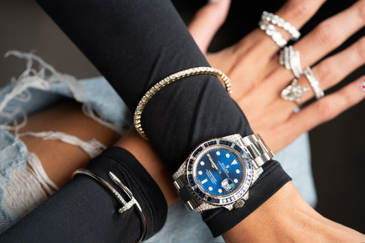 A blue dial Rolex Submariner with a stone set bezel worn alongside bracelets.
