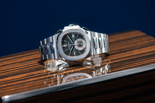 A Patek Philippe Nautilus with a dark dial on a wooden surface.