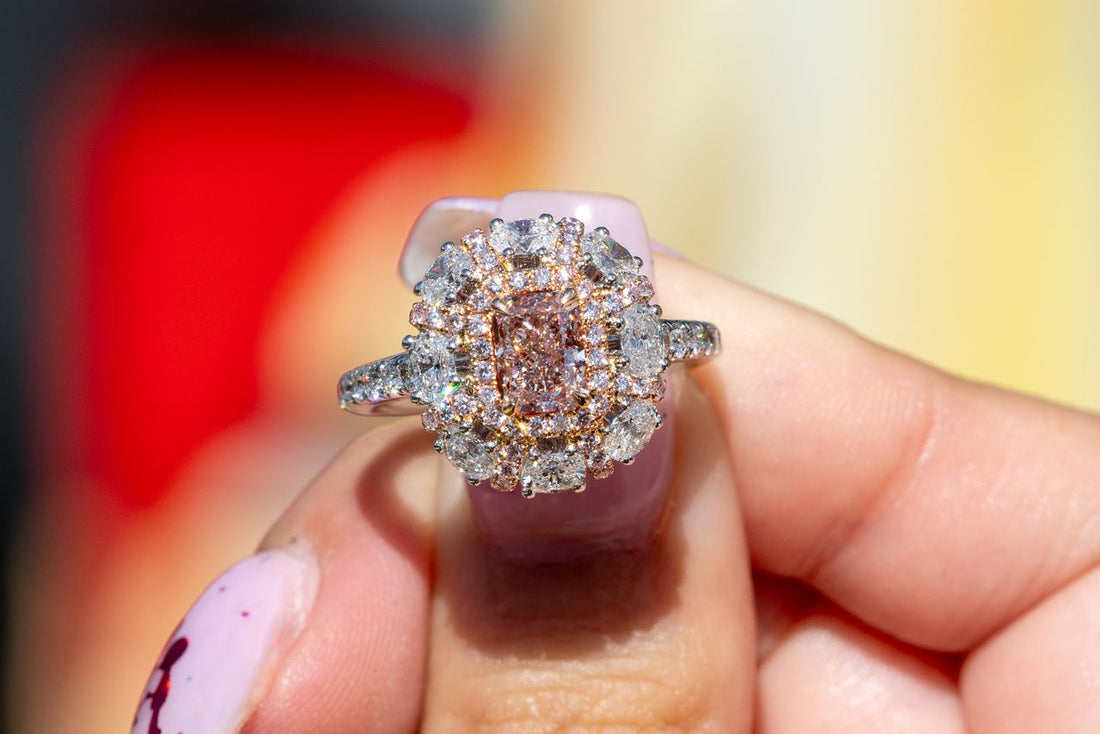 A ring with a rectangular pink center stone and surrounding white stones.