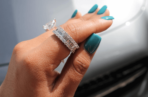 Pear shaped ring and diamond band beside a car, with turquoise nails.