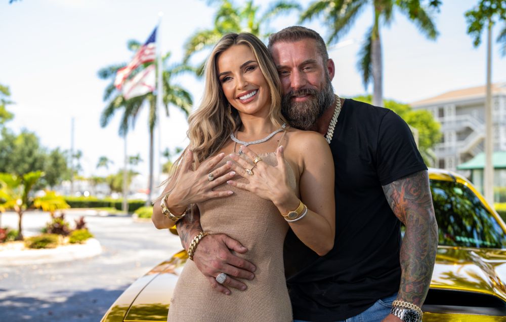 Two models wearing jewelry beside a gold colored car.