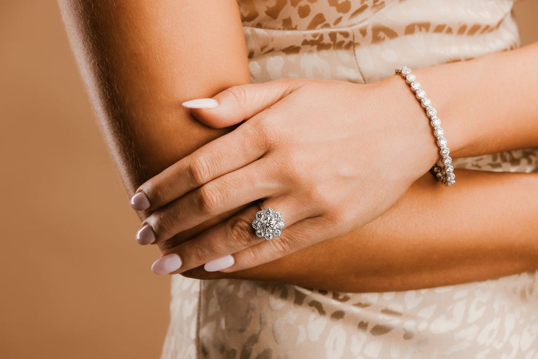 A cluster ring and round stone bracelet shown on the hand and wrist.