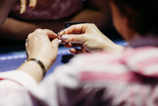 Hands holding a ring above a jewelry counter.