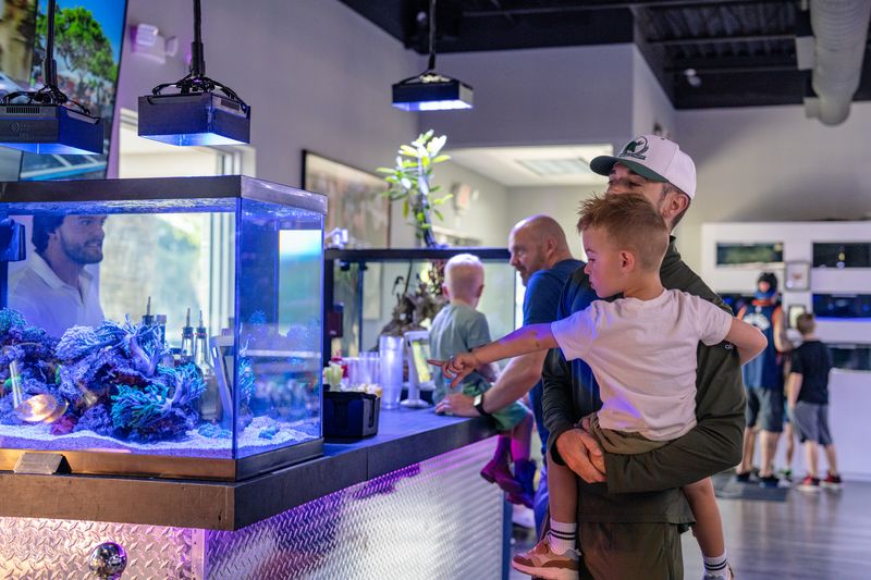 An adult carrying a child and pointing toward an aquarium.