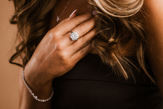 A hand wearing a cluster style ring and a bracelet.