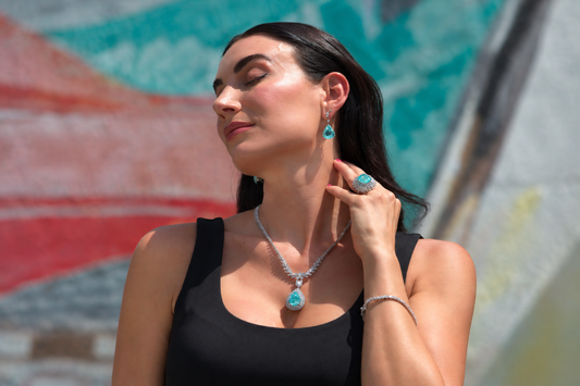 Blue toned earrings, pendant and ring worn together outdoors.