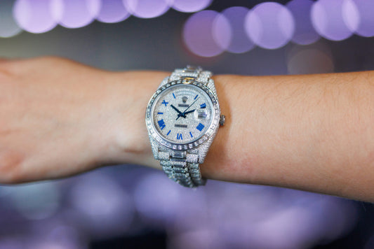 A Rolex watch with stone set dial, bezel and bracelet worn on the wrist.