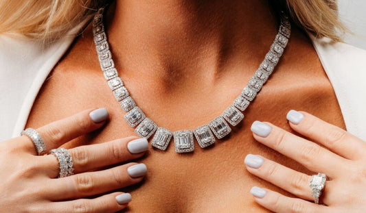 A necklace with rectangular stone clusters, worn with several rings.