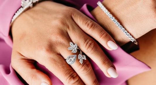 A floral ring with a pear shaped center, worn beside a bracelet.