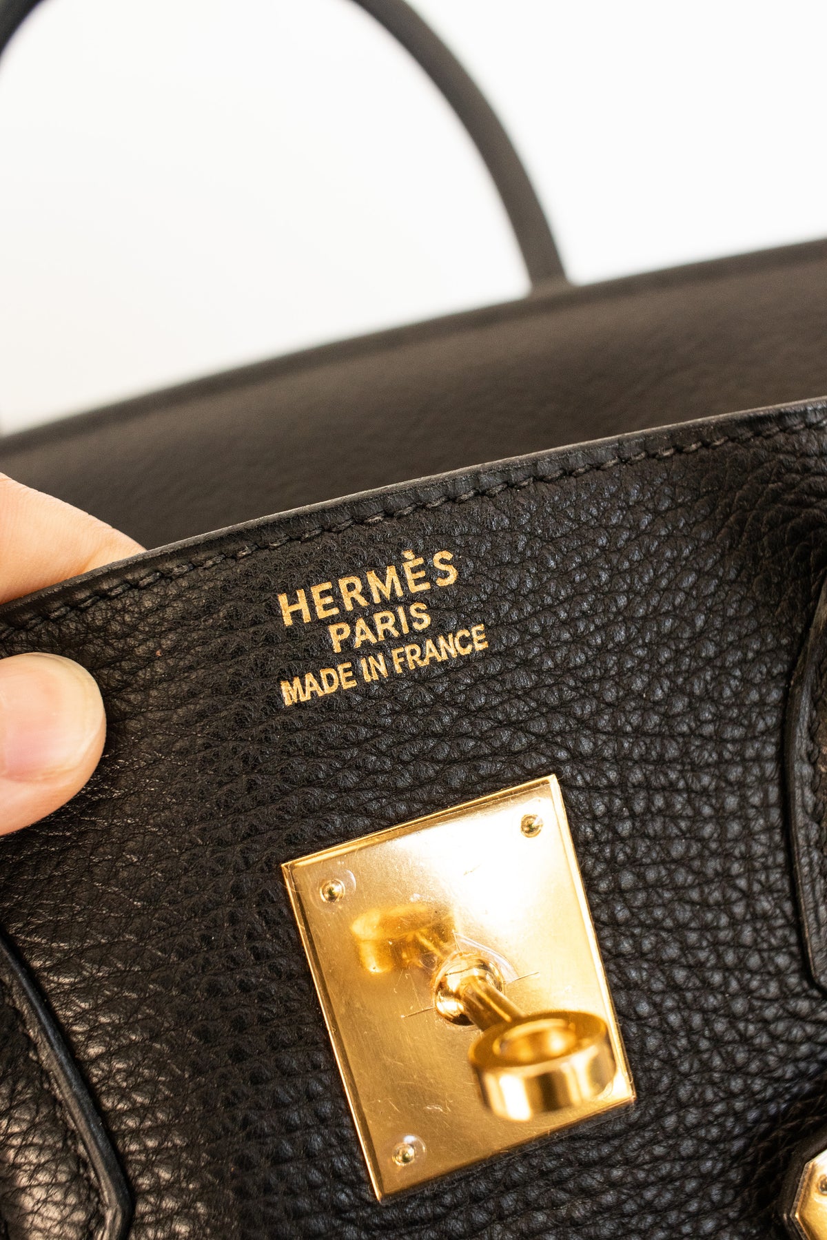 Hermès Paris stamp and gold tone turn lock on a black leather handbag