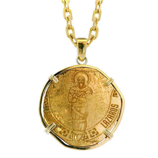 Gold pendant necklace with a religious design on a white background