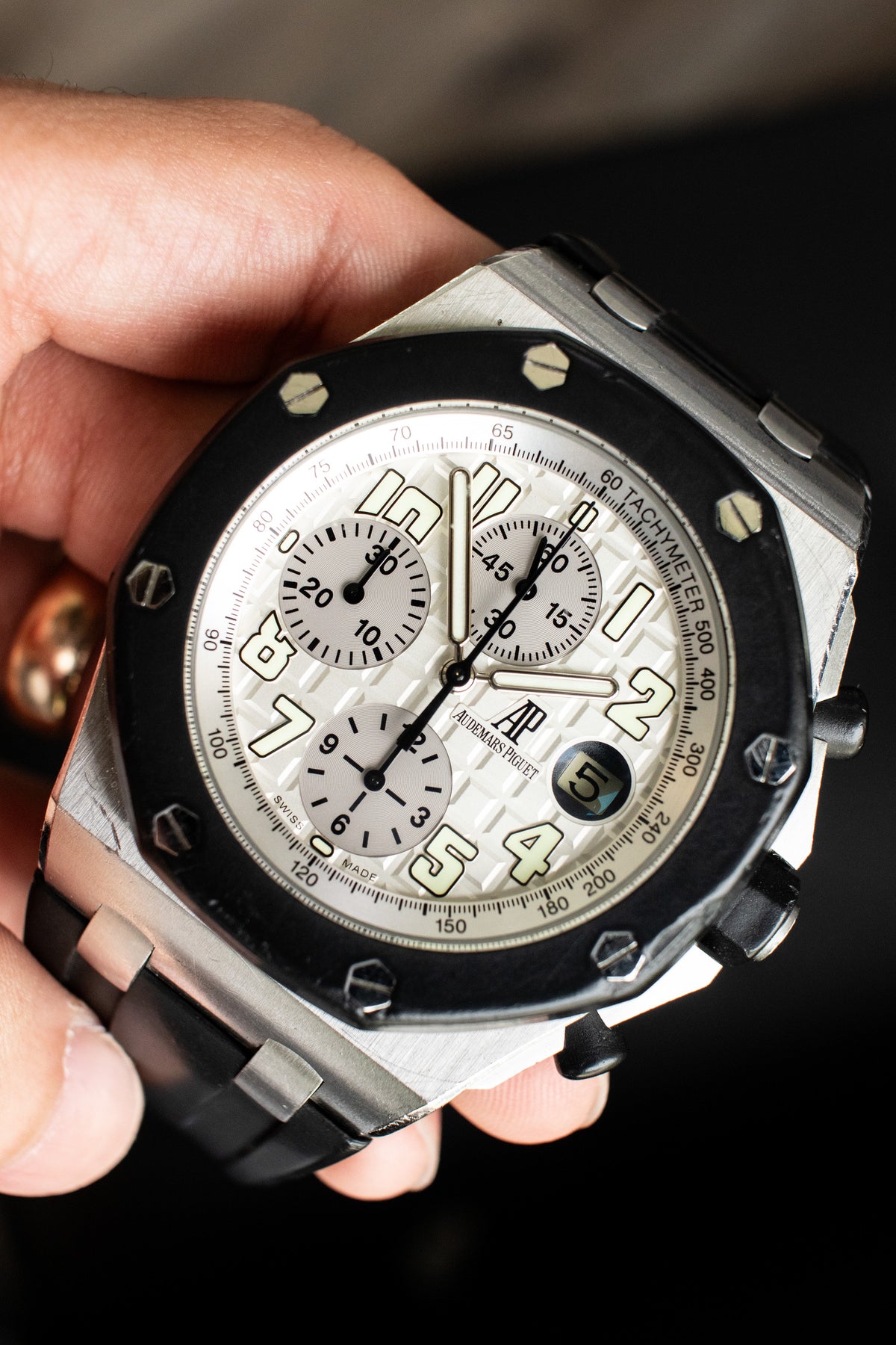 Audemars Piguet chronograph with a light dial and black bezel held in a hand