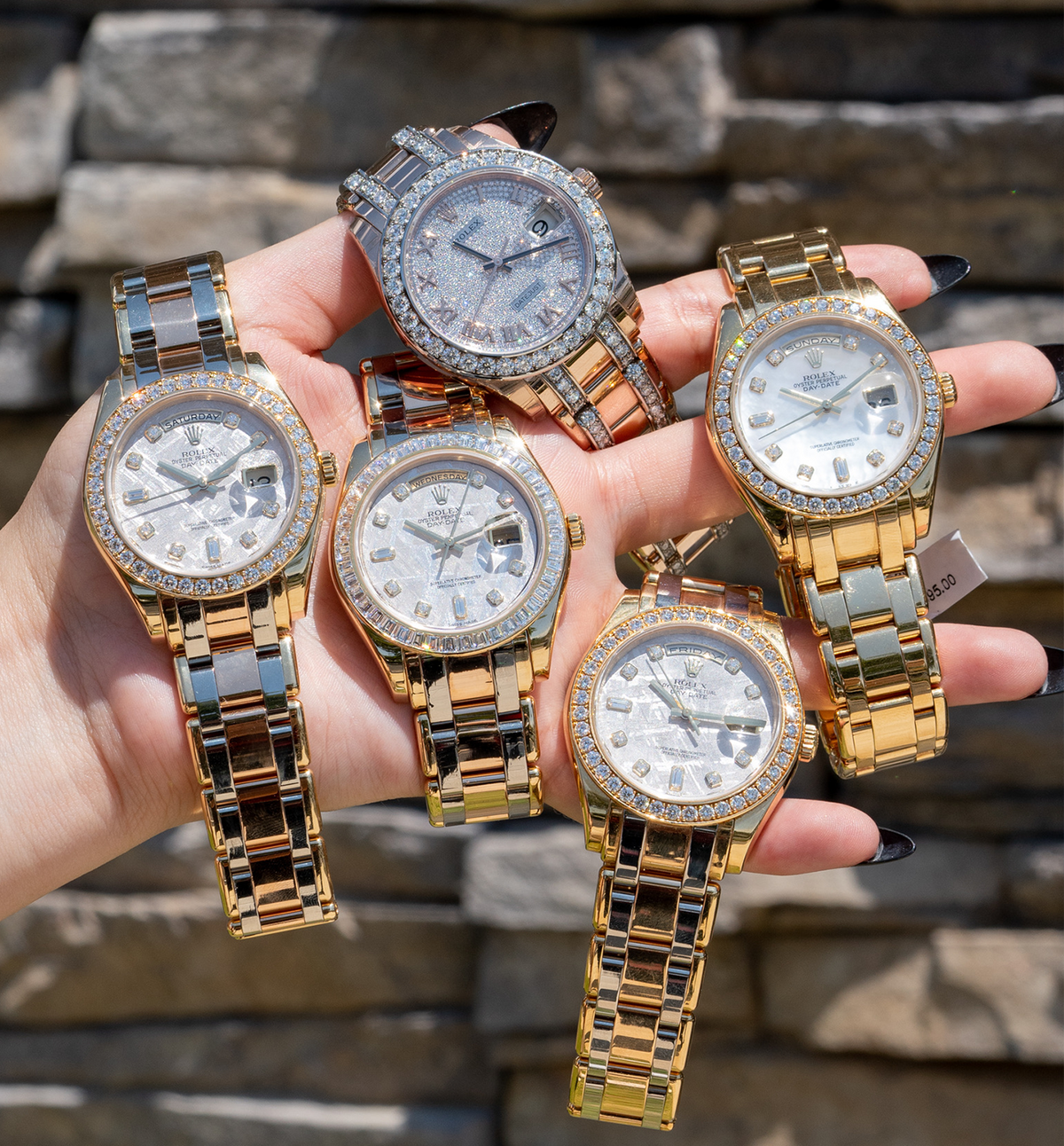 Several two tone watches held in one hand