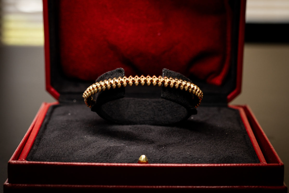 Gold-tone Cartier bracelet inside a red presentation box