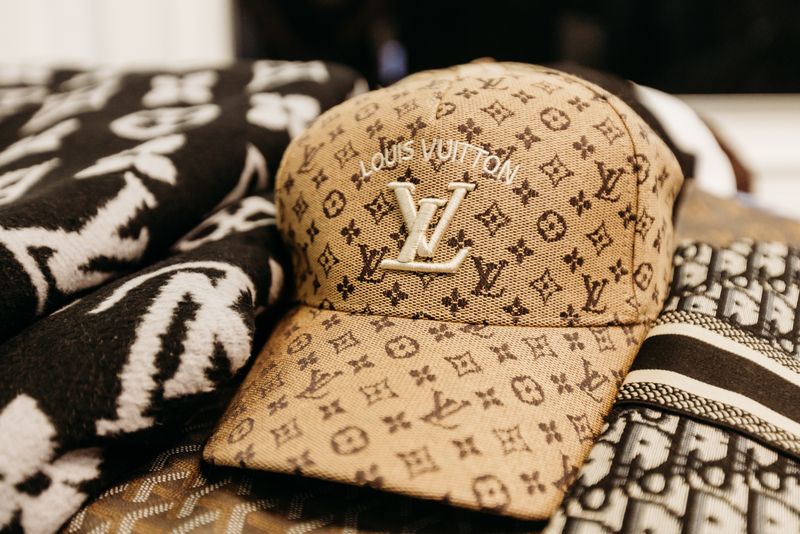 Tan Louis Vuitton monogram cap displayed with patterned accessories