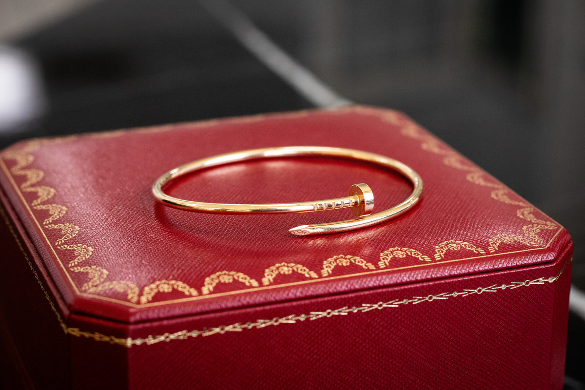 Gold-tone Cartier bracelet resting on a red box