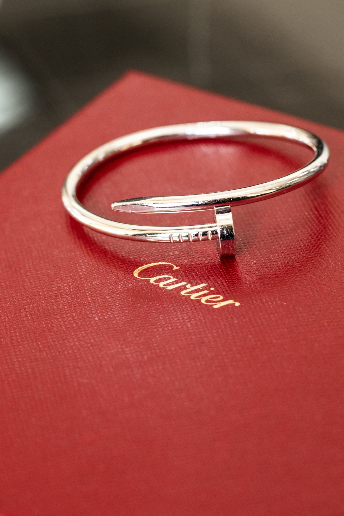Polished nail shaped bracelet resting on a red Cartier box