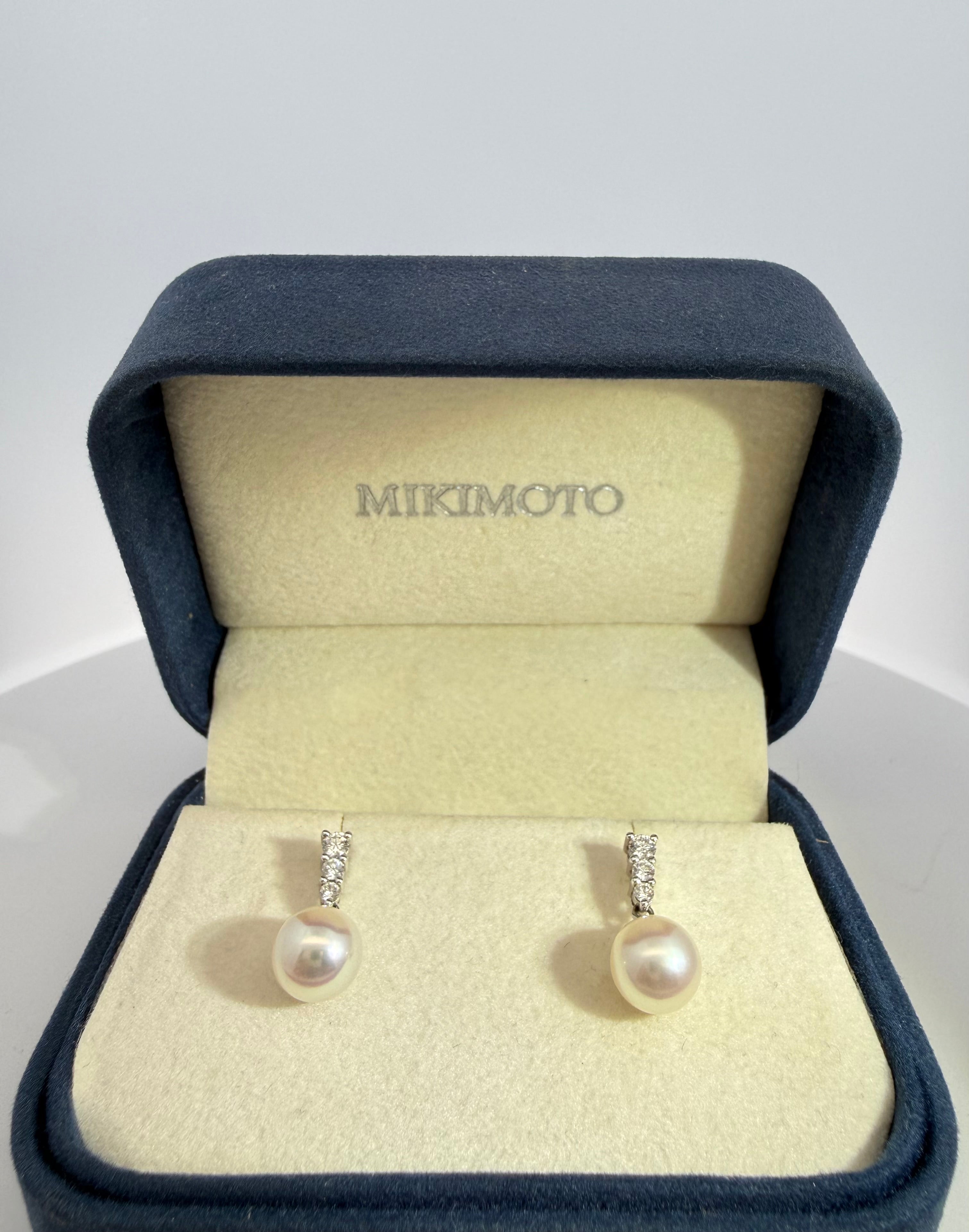 Pearl earrings in a Mikimoto box on a light gray background