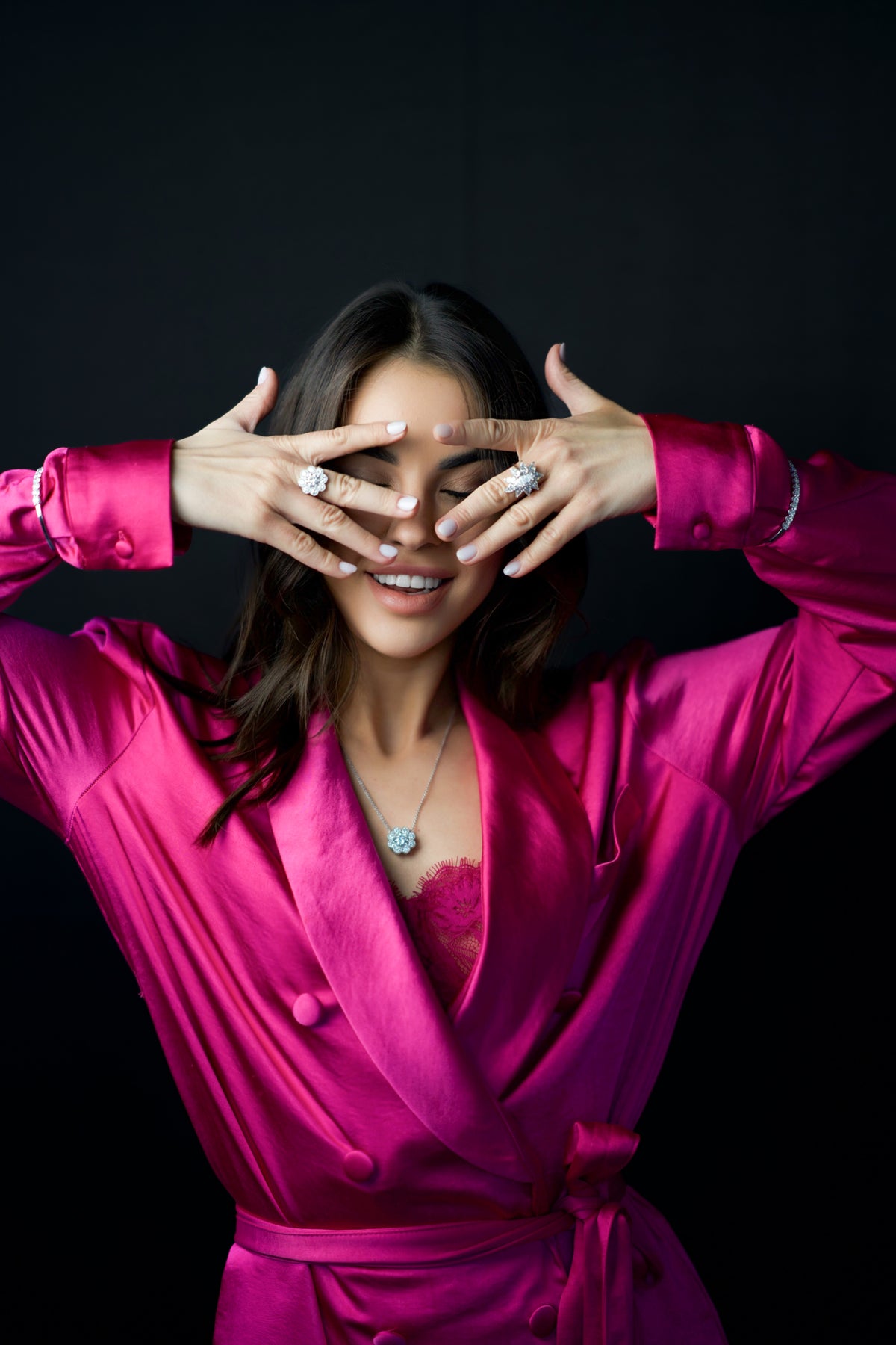 Model in a pink outfit wearing rings and a pendant necklace
