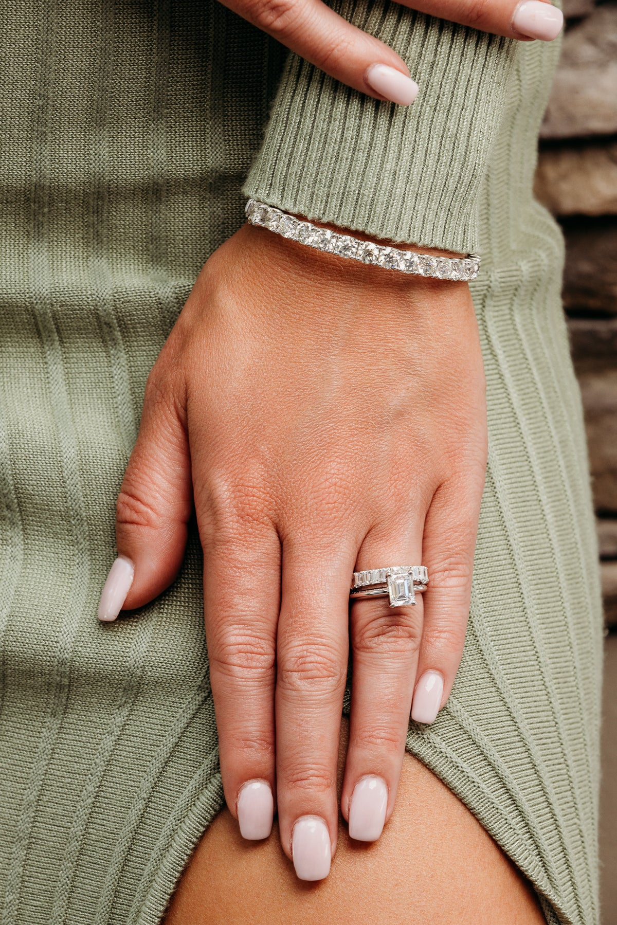 Rectangular center stone ring, matching band and tennis bracelet worn with a green knit sleeve