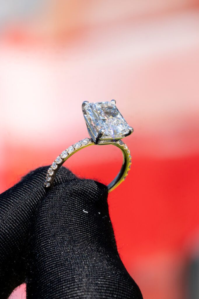 Square center-stone ring held in a gloved hand