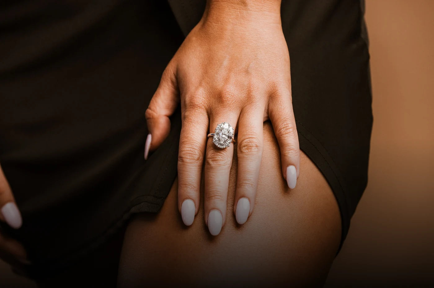 A model wearing an oval diamond ring with a halo and diamond-set band.