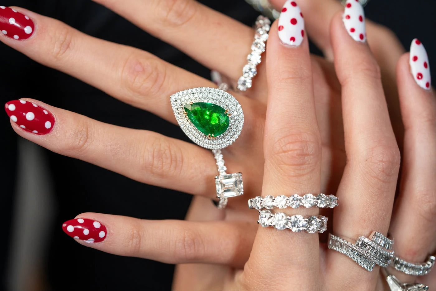 Hands wearing gemstone rings and a tennis bracelet
