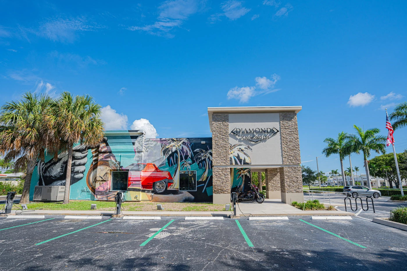 The freestanding Diamonds by Raymond Lee building in Boca Raton, with its colorful exterior mural and palm trees.