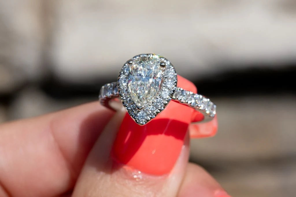 Ring with a pear shaped center stone and a halo setting