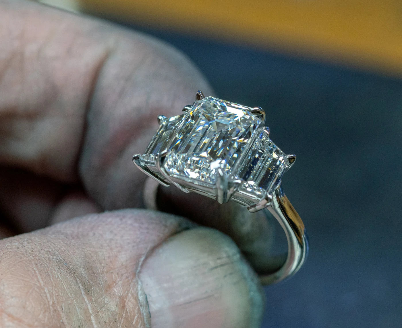Rectangular center stone ring held between fingers