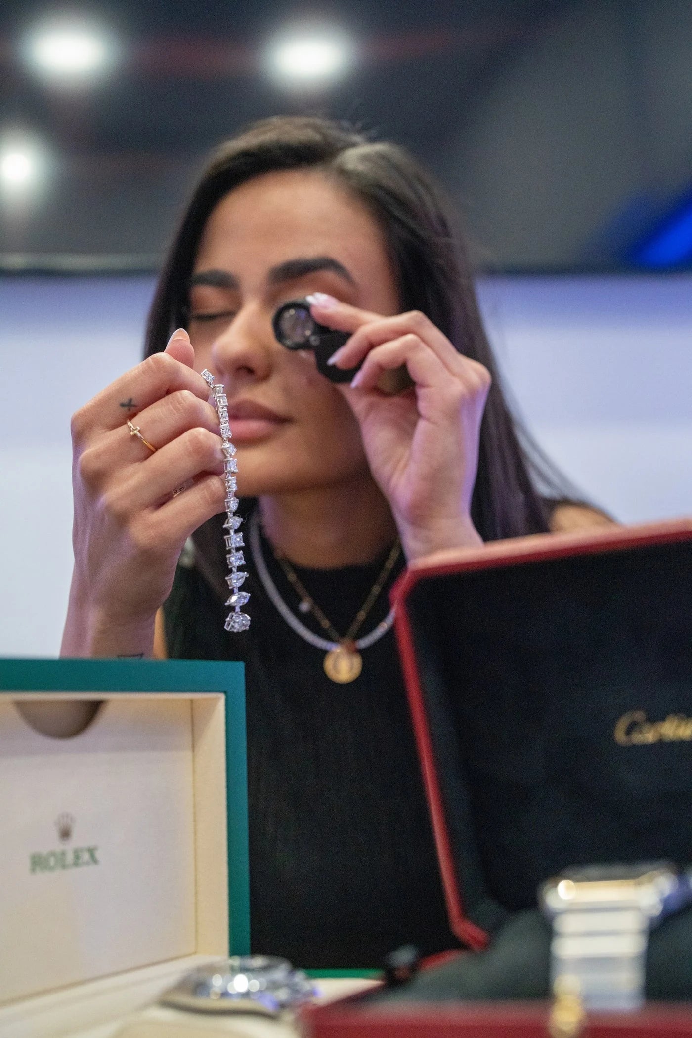 A team member examining jewelry through a loupe at the counter