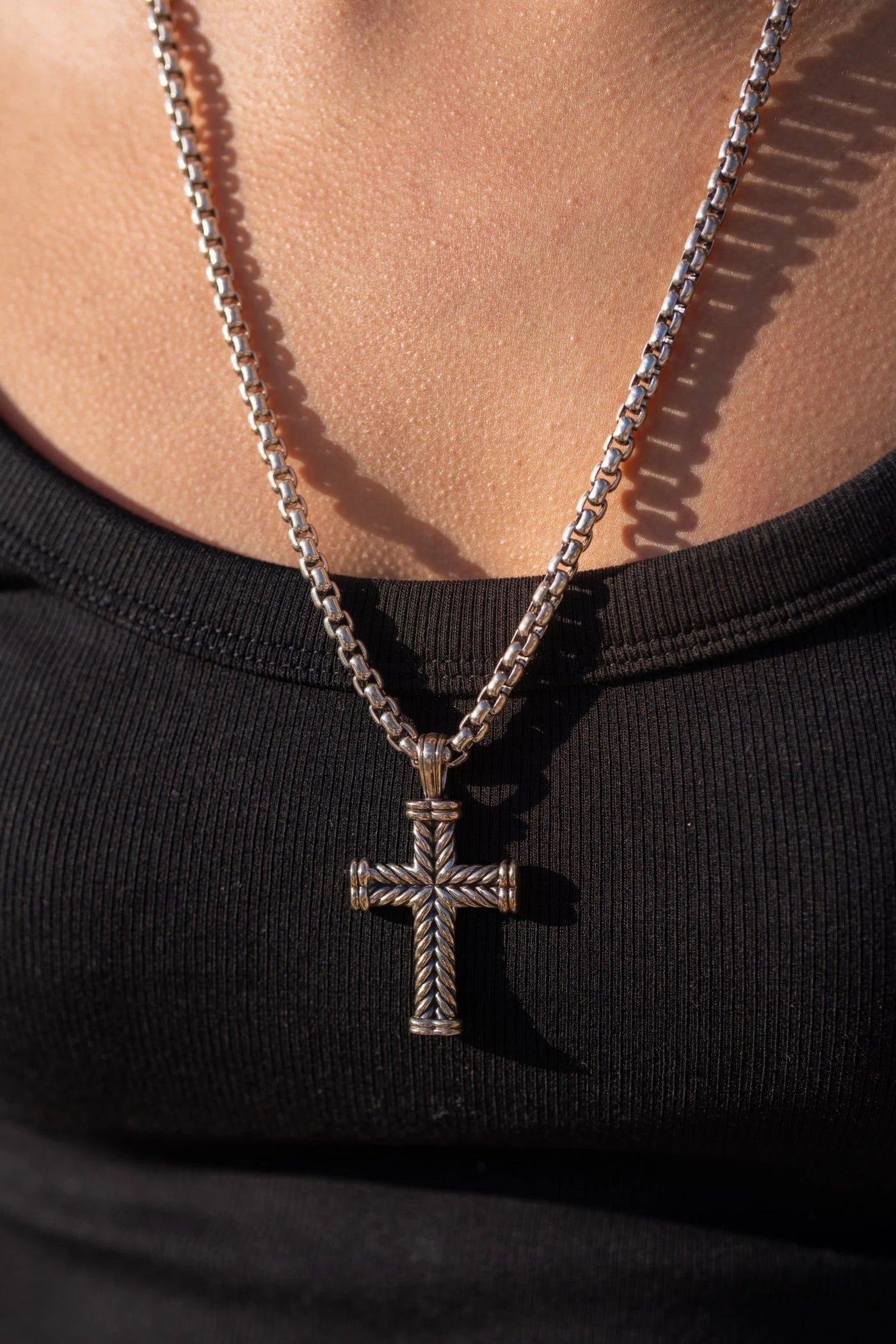 Cross pendant on a chain worn over a dark top