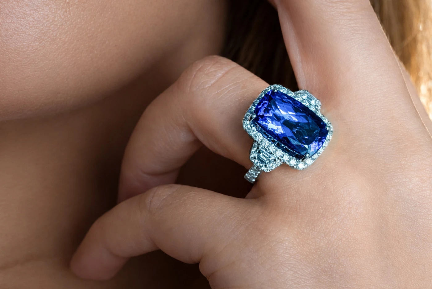 Cushion-shaped blue-violet center stone ring worn on a hand