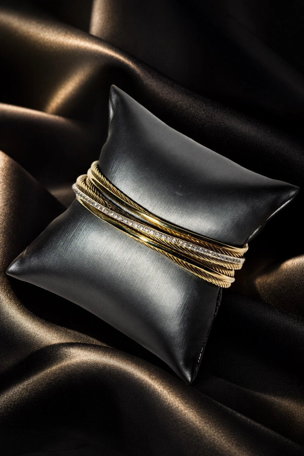 Stacked cable bangles on a dark jewelry display