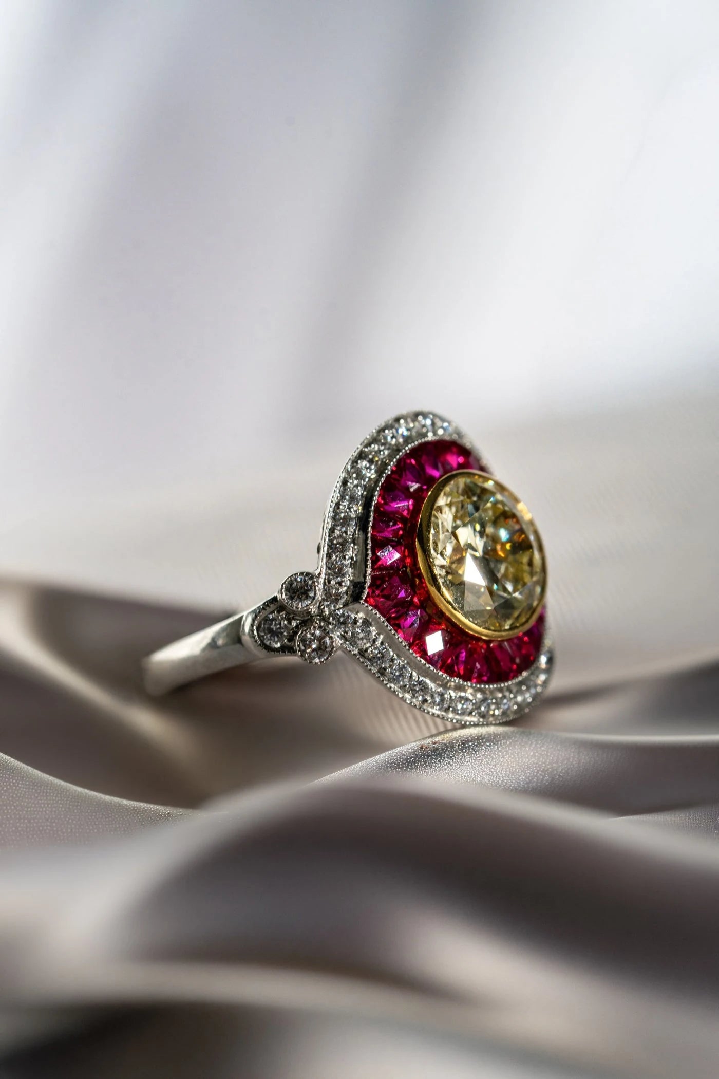 Oval yellow center stone surrounded by red gemstones in a ring